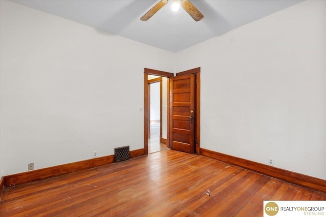 empty room featuring ceiling fan, visible vents, baseboards, and hardwood / wood-style floors