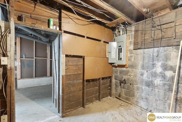unfinished basement featuring concrete block wall and electric panel