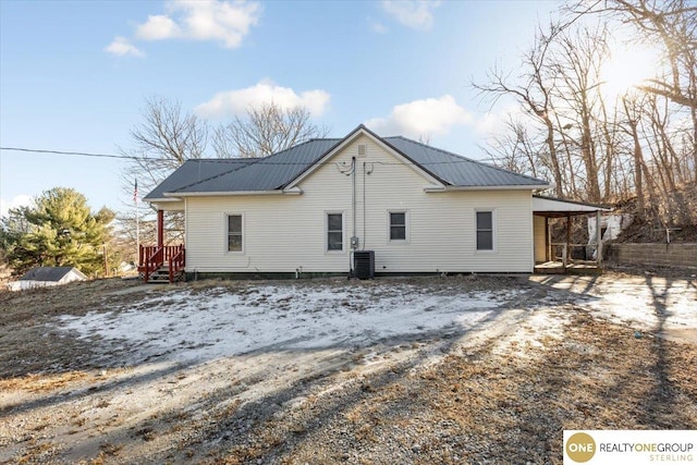back of property featuring central AC unit and metal roof