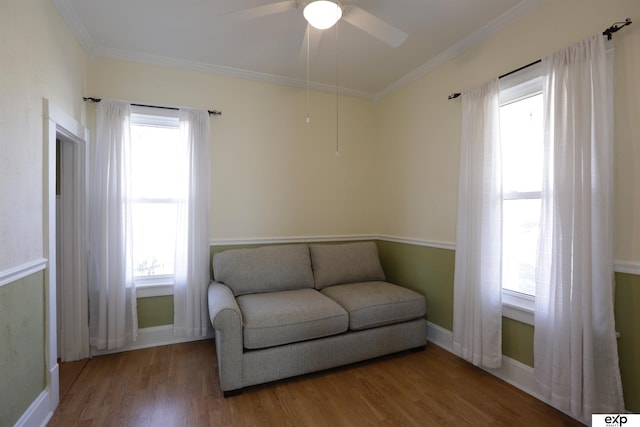 sitting room featuring plenty of natural light, wood finished floors, and ornamental molding