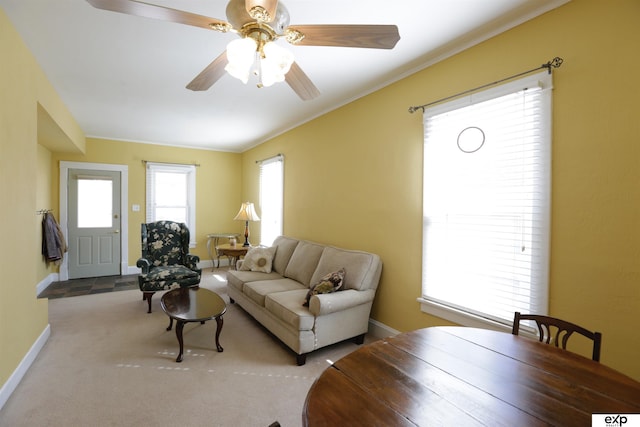 carpeted living room with a ceiling fan, baseboards, and ornamental molding