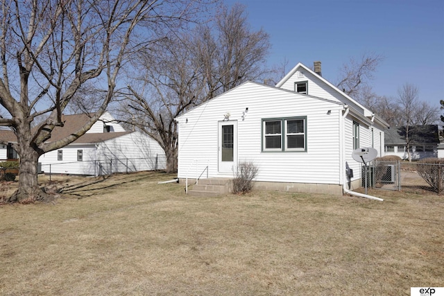 rear view of property with a gate, a chimney, a yard, and fence