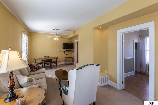 carpeted living area with visible vents, ceiling fan, and baseboards