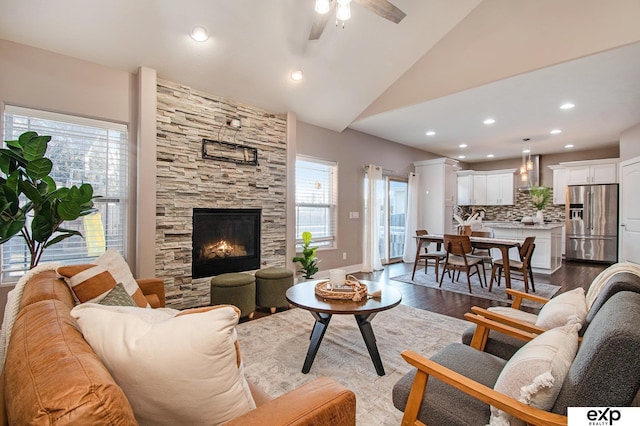 living area with a ceiling fan, baseboards, recessed lighting, a stone fireplace, and dark wood-type flooring