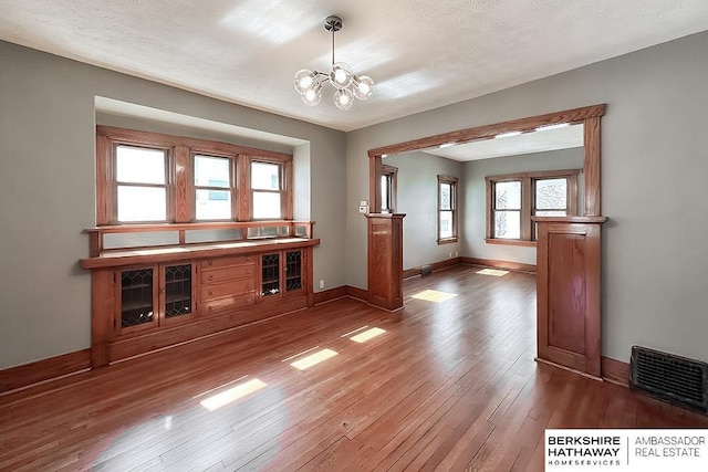 interior space with visible vents, baseboards, a chandelier, hardwood / wood-style floors, and a textured ceiling