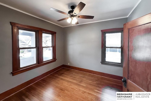 unfurnished room with a ceiling fan, wood-type flooring, baseboards, and ornamental molding