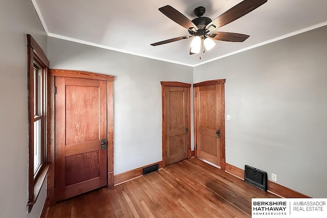 unfurnished bedroom featuring visible vents, wood finished floors, baseboards, and ornamental molding