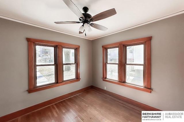 empty room with ceiling fan, baseboards, wood finished floors, and ornamental molding