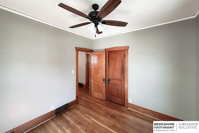 unfurnished bedroom featuring baseboards, visible vents, ceiling fan, ornamental molding, and light wood-type flooring