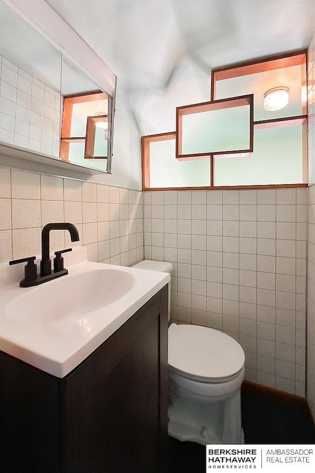 bathroom featuring toilet, tile walls, and vanity