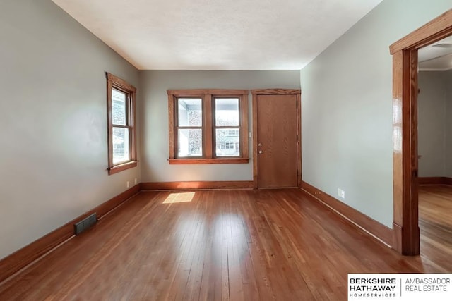 unfurnished room with hardwood / wood-style flooring, baseboards, and visible vents