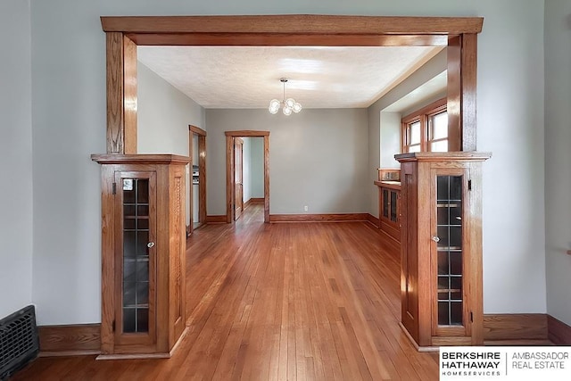 hall featuring visible vents, an inviting chandelier, baseboards, and light wood-style floors