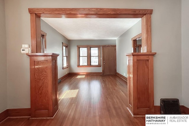 unfurnished living room with visible vents, baseboards, a textured ceiling, and wood finished floors