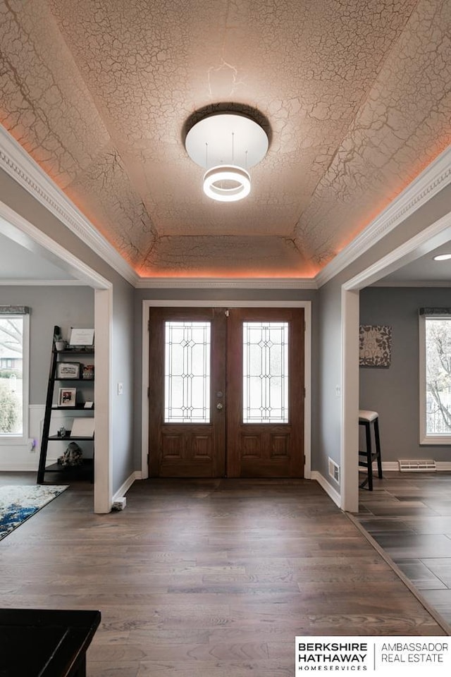 foyer featuring a tray ceiling, visible vents, wood finished floors, and ornamental molding