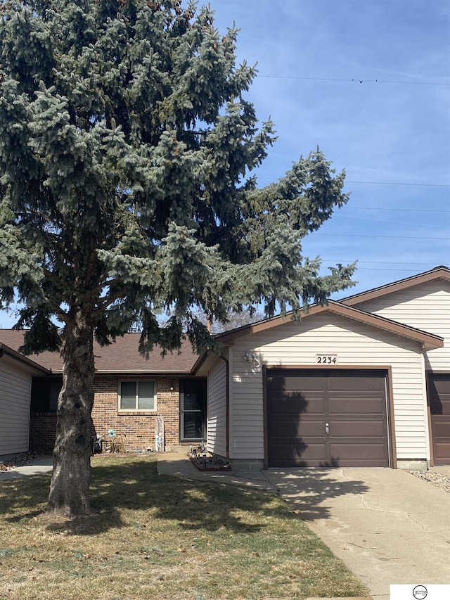 single story home featuring a garage, concrete driveway, and a front yard