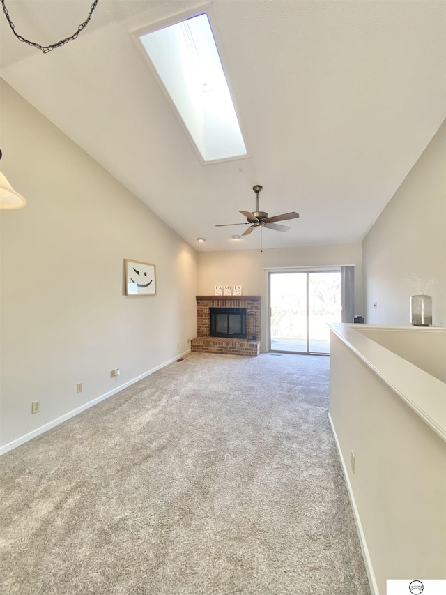 unfurnished living room featuring baseboards, lofted ceiling with skylight, carpet floors, and a fireplace