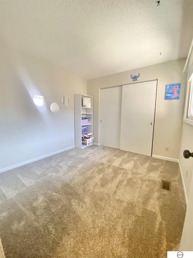 unfurnished bedroom featuring baseboards, visible vents, a closet, a textured ceiling, and carpet flooring