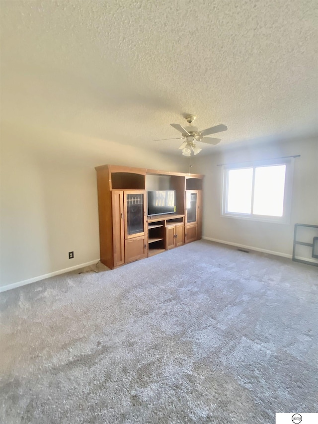 unfurnished living room featuring baseboards, a textured ceiling, ceiling fan, and carpet flooring