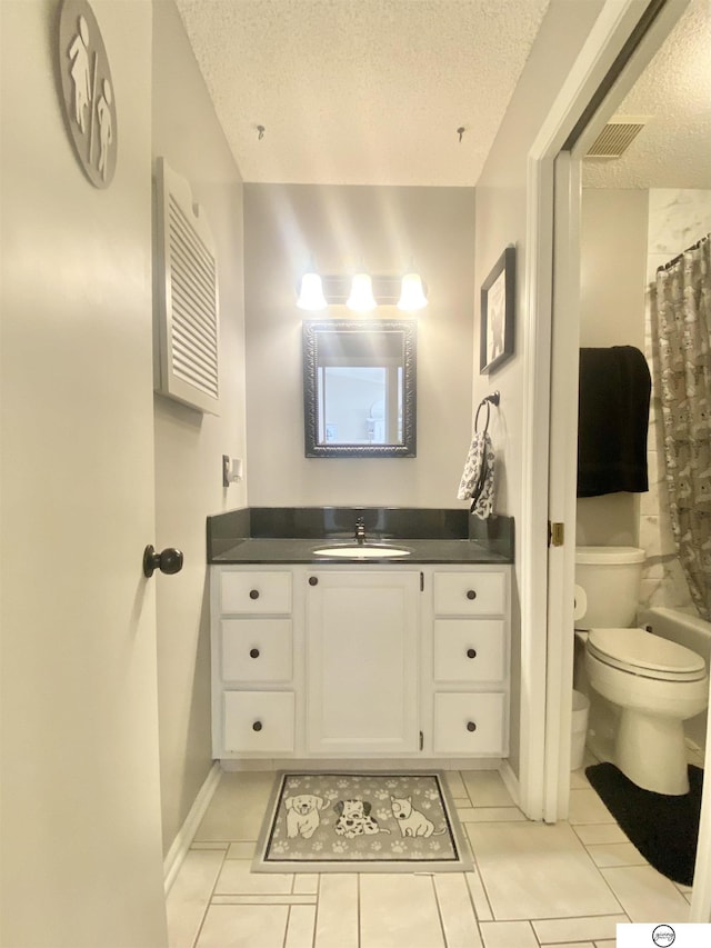 bathroom with visible vents, toilet, vanity, tile patterned floors, and a textured ceiling