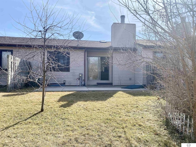 rear view of property with a yard, a patio area, and a chimney