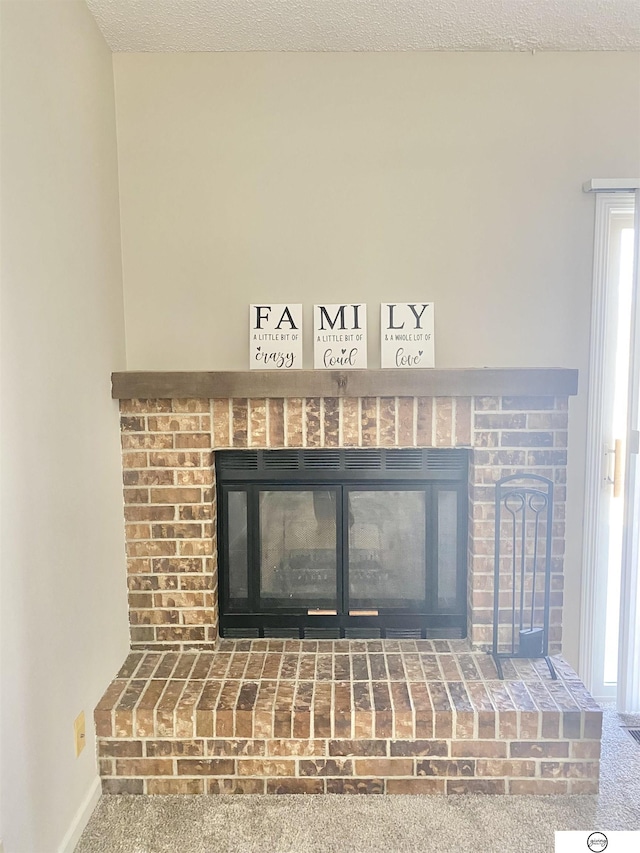 interior details featuring a fireplace, a textured ceiling, baseboards, and carpet floors