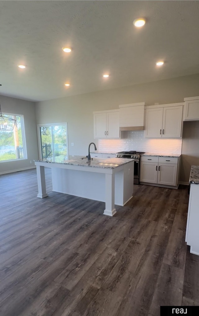 kitchen featuring light stone countertops, stainless steel range with gas stovetop, dark wood-style flooring, and white cabinetry