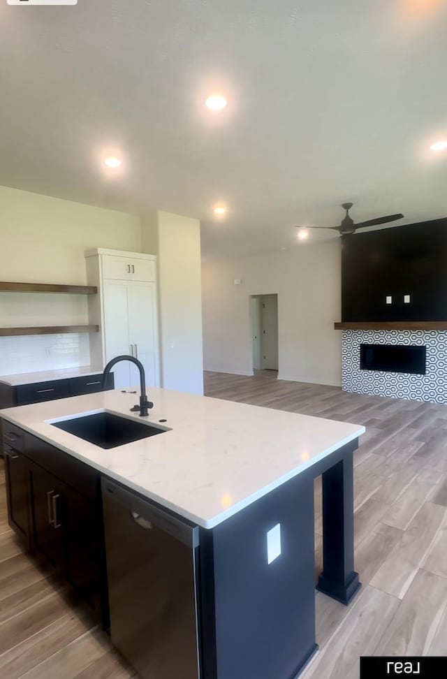 kitchen featuring a sink, light wood-type flooring, stainless steel dishwasher, and ceiling fan