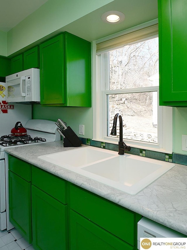 kitchen with a sink, white appliances, and green cabinetry