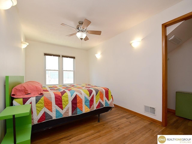 bedroom featuring visible vents, ceiling fan, baseboards, and wood finished floors