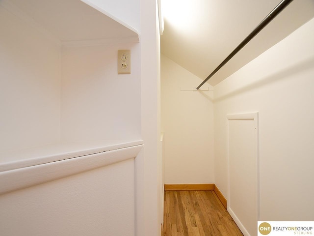 walk in closet with light wood-style flooring and vaulted ceiling