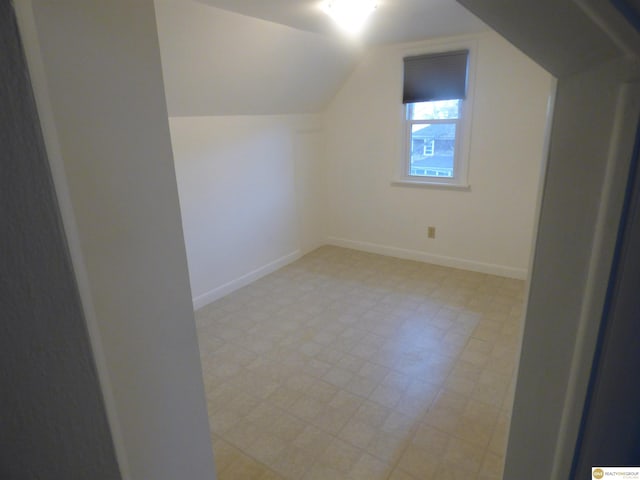 bonus room featuring baseboards, light floors, and lofted ceiling