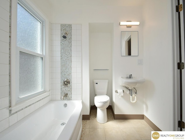 bathroom with baseboards, tub / shower combination, a sink, tile patterned flooring, and toilet