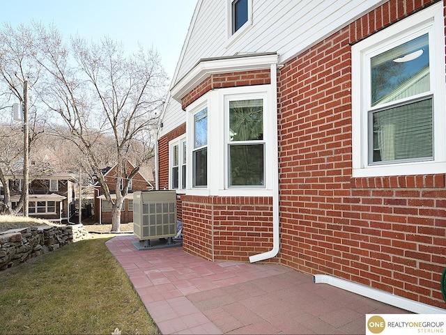 view of side of home featuring a patio and brick siding