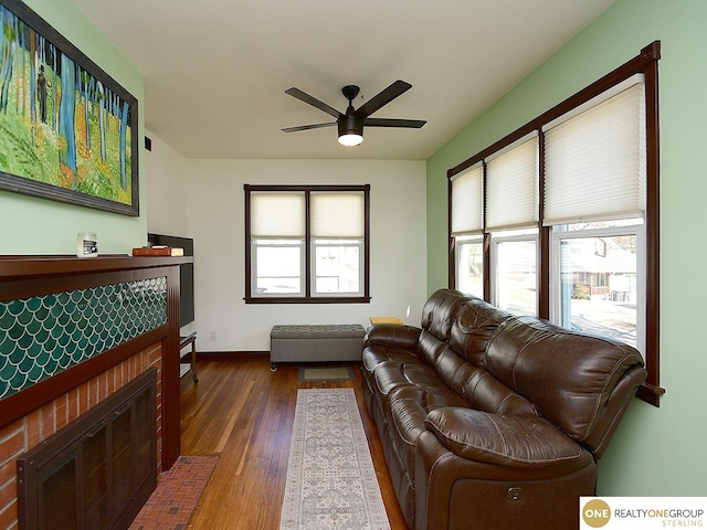 living room featuring plenty of natural light, baseboards, ceiling fan, and wood finished floors