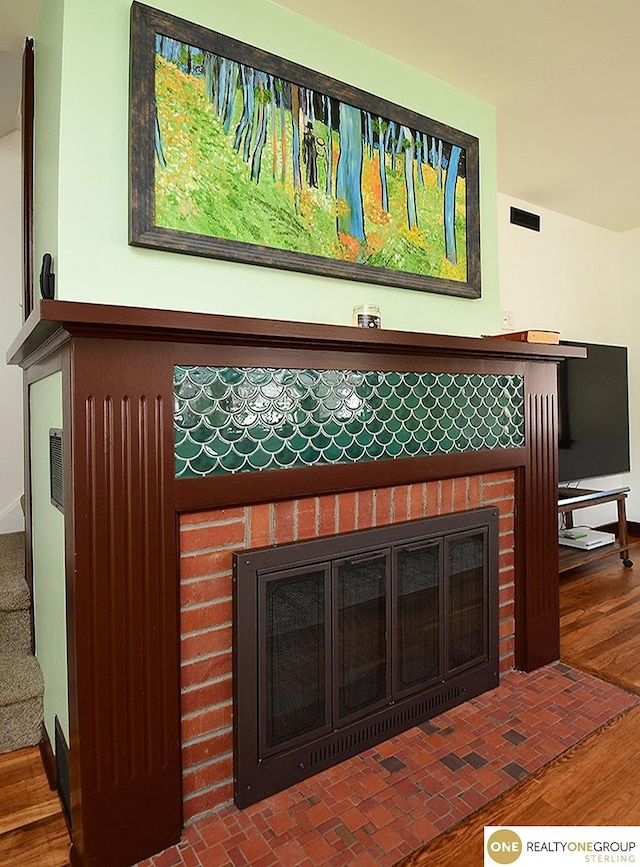 interior details featuring visible vents, a brick fireplace, and wood finished floors