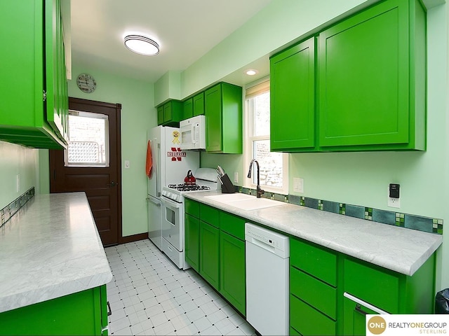 kitchen featuring a sink, white appliances, light countertops, green cabinetry, and light floors