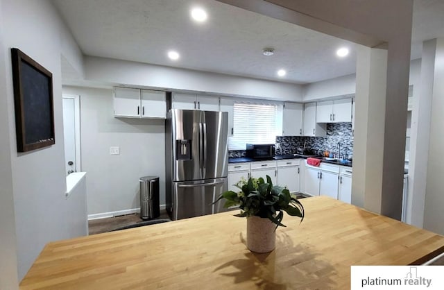 kitchen with decorative backsplash, stainless steel fridge, and white cabinets