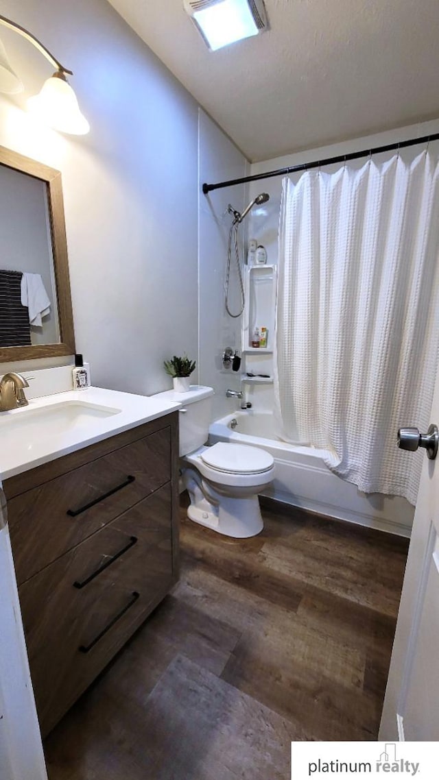 bathroom with toilet, wood finished floors, vanity, and shower / bath combo