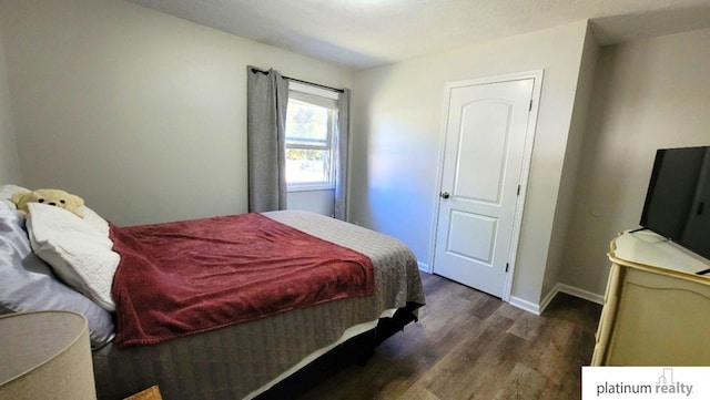 bedroom with dark wood-type flooring and baseboards