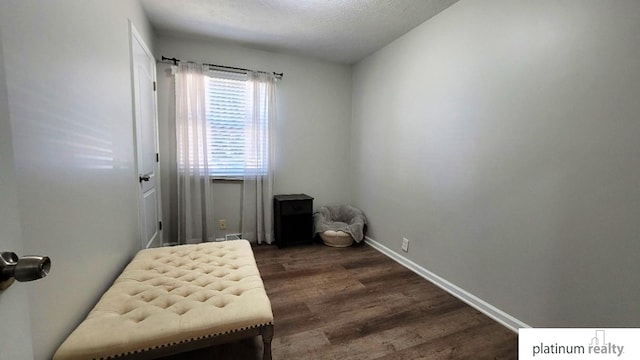 sitting room with a textured ceiling, baseboards, and wood finished floors