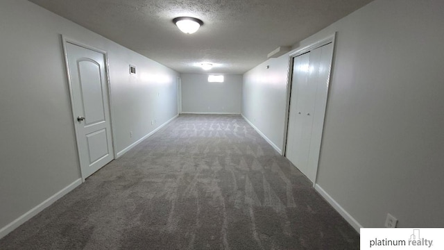 corridor featuring visible vents, carpet floors, a textured ceiling, and baseboards