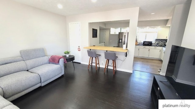 living area featuring recessed lighting, baseboards, and dark wood-style flooring