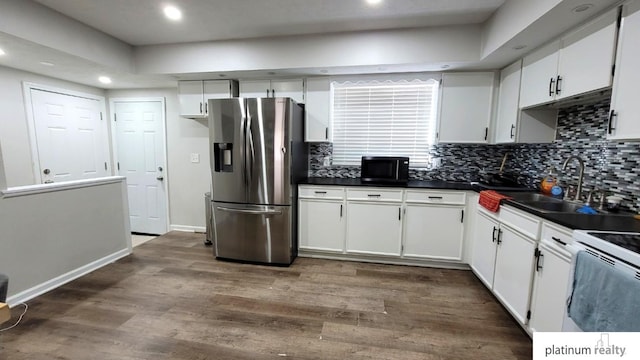 kitchen with stainless steel refrigerator with ice dispenser, a sink, dark countertops, black microwave, and dark wood-style flooring