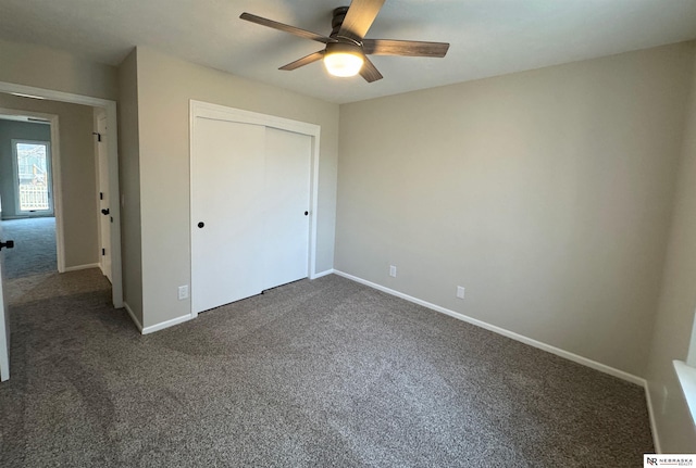 unfurnished bedroom with a ceiling fan, baseboards, dark colored carpet, and a closet