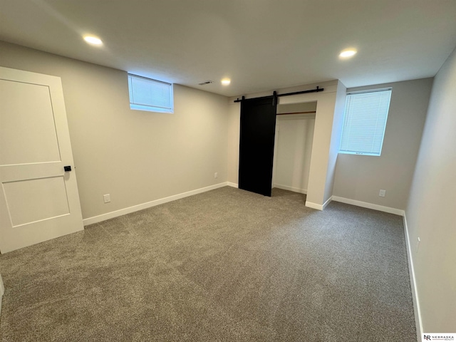 unfurnished bedroom featuring recessed lighting, a barn door, carpet floors, and baseboards