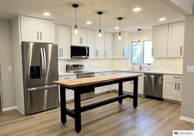 kitchen with light wood-style flooring, a sink, white cabinetry, stainless steel appliances, and decorative backsplash