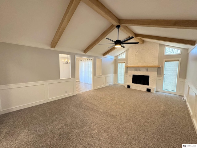 unfurnished living room featuring a wainscoted wall, a ceiling fan, a decorative wall, a fireplace, and carpet flooring