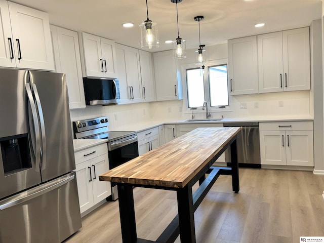 kitchen featuring a sink, light wood-style floors, backsplash, and stainless steel appliances