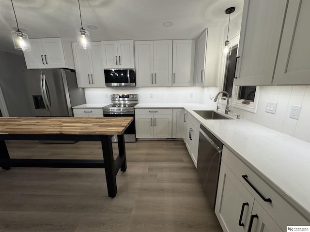 kitchen with a sink, stainless steel appliances, pendant lighting, and wood counters