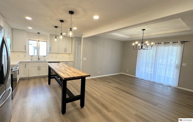 kitchen featuring a sink, a tray ceiling, an inviting chandelier, and wood finished floors